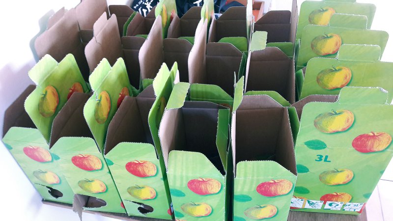 Die leeren Kartons warten auf die abgefüllten Apfelsaft-Beutel